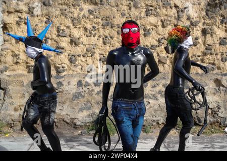 März 2024, San Nicolas de los Ranchos, Mexiko: Jugendliche mit schwarz lackiertem Körper und Masken nehmen an der vorspanischsprachigen Feier „der Karneval der Xinacates“ Teil, die in San Nicolas de los Ranchos, Gemeinde an den Hängen des Vulkans Popocatepetl, im Bundesstaat Puebla stattfindet. Als Teil der Tradition gehen die Xinacates oder gemalten Menschen auf die Straßen, um Touristen zu malen. Während dieser Feierlichkeiten wird dem Teoton-Vulkan Tribut gezollt, damit die Bewohner eine gute Erntezeit haben. Am 3. März 2024 in San Nicolas de los Ranchos, Mexiko. (Kredit-Imag Stockfoto