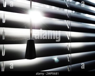 Jalousien auf dem Fenster Ein Lichtstrahl zwischen den Streifen Beleuchtungsregler Stockfoto