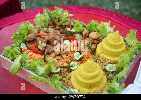 Tumpeng ist ein typisches indonesisches Reisgericht, das wie ein Kegel geformt ist und Gemüse- und Fleischbeilagen in Form eines Kegels enthält. Stockfoto