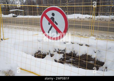 Kein Durchgangsschild, nicht passieren. Der Mann hat eine rote Linie durchgestrichen. Rundes Verkehrsverbot. Verboten. Ein Loch, das in den Boden gegraben wurde, umgeben von einem Metall Stockfoto