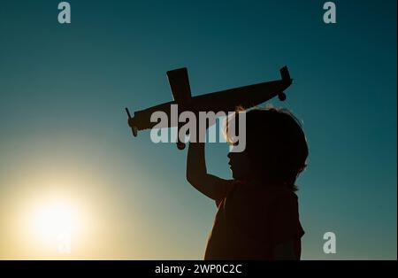 Kinderträume. Junge Pilot mit Spielzeug Flugzeug, Silhouette. Kinder spielen im Freien. Frohe Kindheit. Tagträumen. Stockfoto