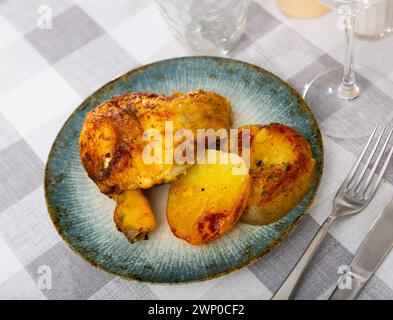 Gebratenes Hähnchen am Schenkel mit Knoblauch in eigenem Saft gewürzt und garniert mit Stücken gebackener Kartoffeln Stockfoto