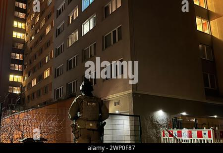 04. März 2024, Berlin: Ein Polizeibeamter steht vor einem Hochhaus in Berlin-Friedrichshain. Die Suche nach den beiden ehemaligen RAF-Terroristen Garweg und Staub hat erneut zu einem größeren Polizeieinsatz durch eine niedersächsische Sondereinsatzgruppe in Berlin-Friedrichshain geführt. Eine Sprecherin des Niedersächsischen Landeskriminalamtes, das für die Operation zuständig war, sagte am Dienstag (05.03.2024), dass es Hinweise auf ein Objekt gegeben habe und Beamte eine Wohnung in einem Studentenwohnheim durchsucht hätten. Foto: Dominik Totaro/dpa Stockfoto