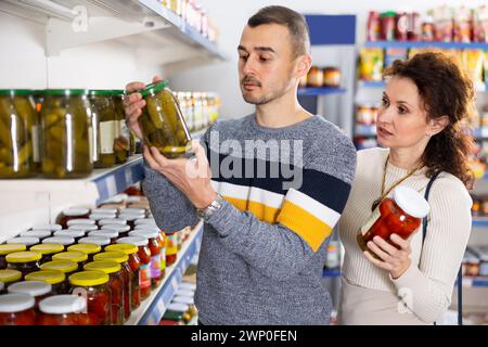 Porträt eines Paares, das im Supermarkt gesalzene Tomaten und Gurken kauft Stockfoto