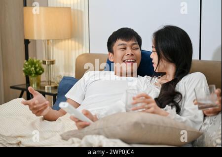 Ein fürsorglicher asiatischer Ehemann spricht mit seiner geliebten Frau, bevor er zusammen ins Bett geht. Das attraktive junge asiatische Paar in Pyjamas ist relaxi Stockfoto