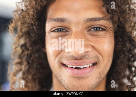 Ein junger birassischer Mann mit lockigen Haaren lächelt warm in die Kamera Stockfoto