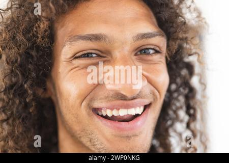 Junger birassischer Mann mit lockigen Haaren lächelt hell Stockfoto