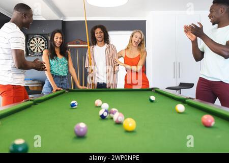 Eine Gruppe von Freunden spielt Billard, während eine junge Frau mit einer Rasse erschossen wird Stockfoto