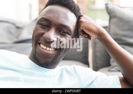 Der junge afroamerikanische Mann lächelt breit und zeigt einen lässigen Stil in einem hellblauen Hemd Stockfoto