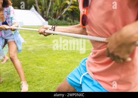 Ein junger Mann und eine Frau, die sich in einem spielerischen Tauziehen im Freien befinden Stockfoto