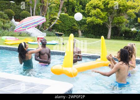 An einem sonnigen Tag spielen verschiedene Freunde eine Runde Volleyball in einem Pool Stockfoto