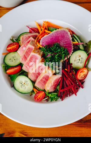 Ein Teller mit einer Vielzahl von Gemüse und Fleisch. Der Teller ist weiß und das Gemüse rot und grün Stockfoto