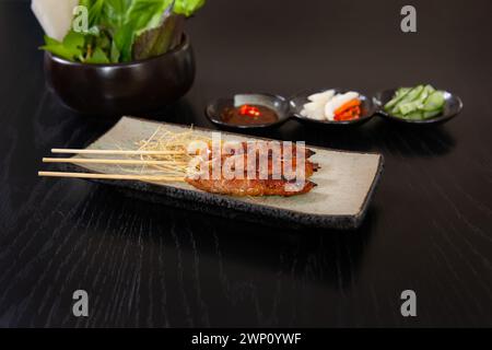 Ne nuong auch bekannt als gegrillte Frühlingsrollen, vietnamesische Speisen isoliert auf schwarzem Holztischhintergrund Stockfoto