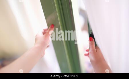 Frau versucht, die Tür zu öffnen, indem sie Fenster oder Türgriff hält Stockfoto