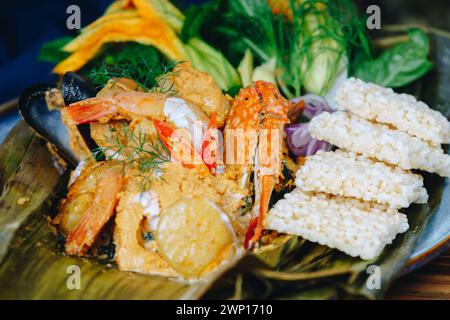 Ein Teller mit Garnelen, Reis und Gemüse. Die Garnelen werden in einer Sauce gekocht und auf Reis serviert. Die Platte wird auf einen Holztisch gestellt Stockfoto