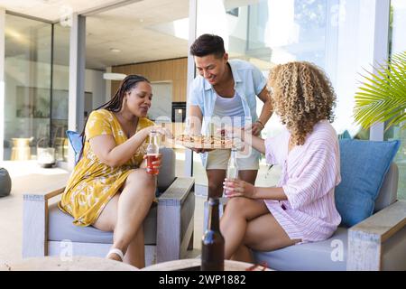 Freunde genießen gemeinsam eine Pizza auf einer sonnigen Terrasse Stockfoto