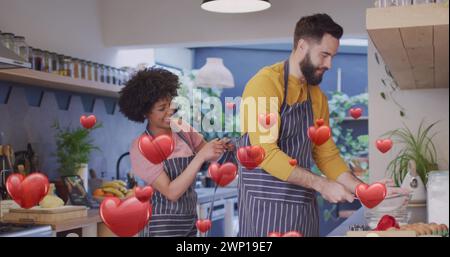 Bild von Herzen und diversen Paaren, die in der Küche Mahlzeiten zubereiten Stockfoto