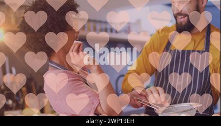 Das Bild von Herzen über ein vielseitiges Paar, das in der Küche Mahlzeiten zubereitete Stockfoto