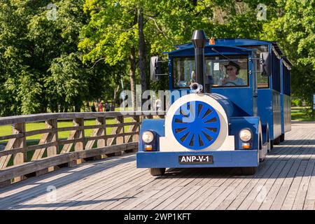 Aluksne, Lettland - 19. Juni 2021: Touristenzug auf der Holzbrücke im Stadtpark Stockfoto