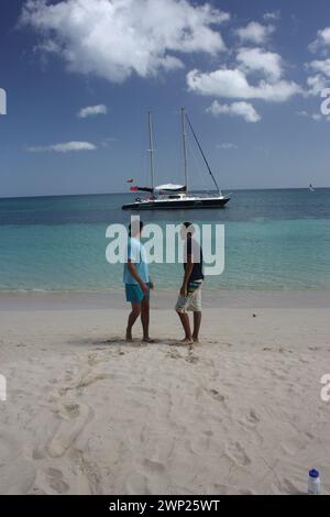 Grand Anse Beach Grenada – zwei Teenager-Jungs warten darauf, an Bord des Shadowfox-Katamarans zu gehen Stockfoto