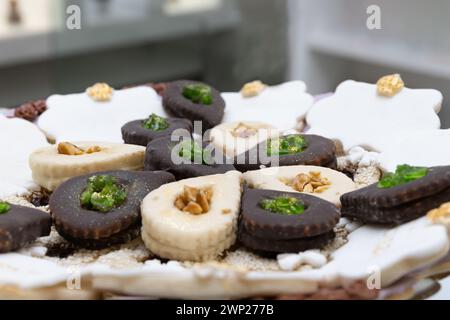 Horizontale Fotos von handwerklich hergestellten arabischen Süßigkeiten, Schokolade und Vanille, verziert mit Nüssen und Minze, präsentiert auf einem traditionellen weißen Teller. Essen und Stockfoto