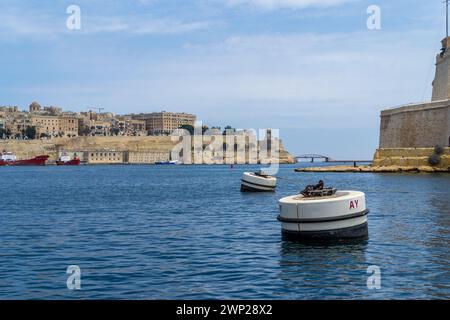 Valletta, Malta - 10. Juni 2016: Bojen im Grand Harbour neben der Spitze von Fort St. Angelo, mit der Stadt Valletta im Hintergrund. Stockfoto