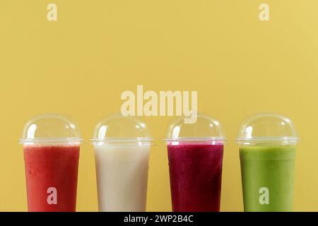 Verschiedene Fruchtsäfte auf Einweg-Plastikbecher mit Deckel, auf gelbem Hintergrund. Kopierbereich für Text Stockfoto