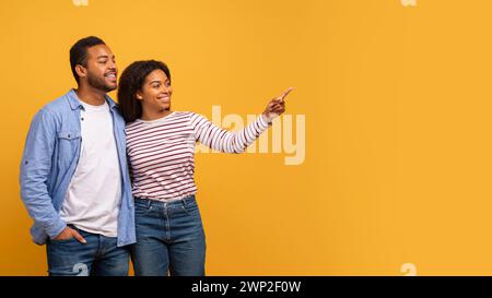 Überprüfen Sie Dies. Glückliche Schwarze Ehepartner Zeigen Mit Dem Finger Auf Den Kopierraum Stockfoto