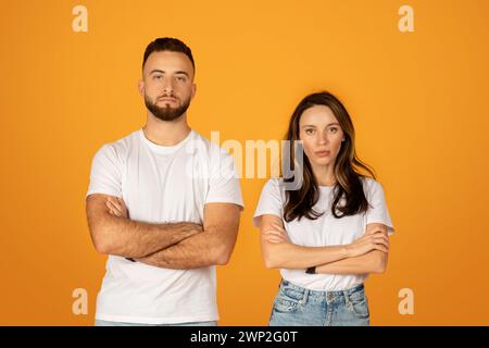 Ernster und selbstbewusster junger Mann und Frau in weißen T-Shirts mit überkreuzten Armen Stockfoto