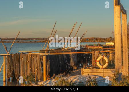 Fischernetze bei Sonnenuntergang auf dem Etang de l'Arnel in Villeneuve-lès-Maguelone in der Nähe von La Camargue, Südfrankreich. Stockfoto