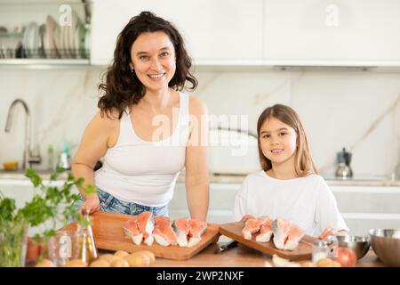 Mom und Tochter bereiten ein festliches Lachsgericht vor. Stockfoto