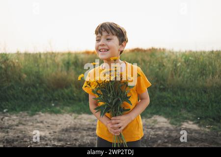Fröhliches, glückliches Kind mit orangenem Blumenstrauß. Stockfoto