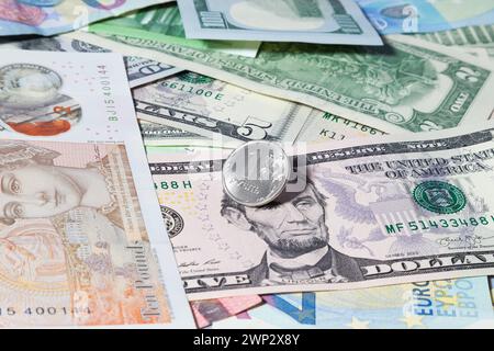 Eine silberfarbene Münze mit einem russischen Rubel liegt auf einer Mischung aus US-amerikanischen und europäischen Banknoten unterschiedlicher Stückelungen - USD, Stockfoto