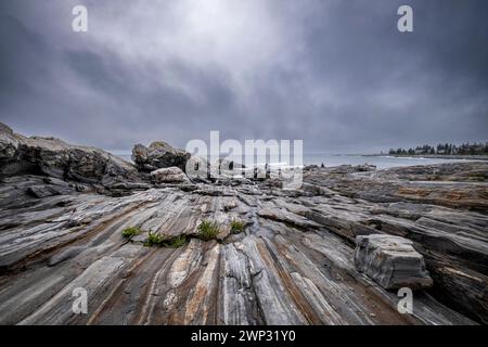 Pemaquid Point, Maine mit bewölktem Himmel und den massiven Felsvorsprüngen im Vordergrund. Stockfoto