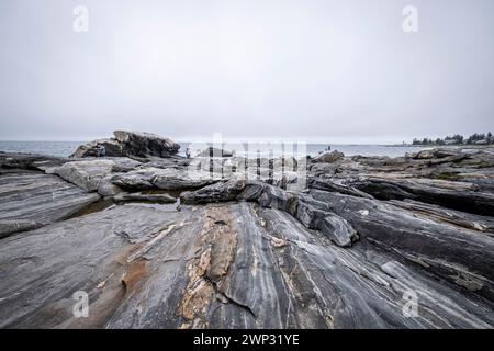 Pemaquid Point, Maine mit bewölktem Himmel und den massiven Felsvorsprüngen im Vordergrund. Stockfoto