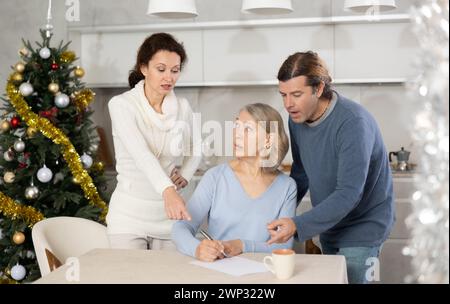 Ein verheiratetes Paar hilft älteren Müttern, an weihnachten Testament in der Küche zu schreiben Stockfoto