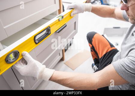 Professioneller Schreiner, der Küchenmöbel Schublade anpasst und Füllstände überprüft Stockfoto