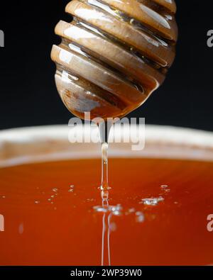 Natürlicher Bio-Honig tropft, gießen aus hölzernem Honiglöffel aus der Nähe Stockfoto