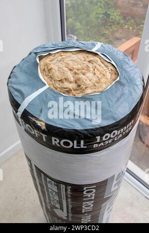 Unbenutzte Rolle mit 100 mm Grundschicht Knauf Loft-Isolierung in Kunststoffverpackung, die an einem Ende in der Ecke eines Wintergartens steht. Stockfoto