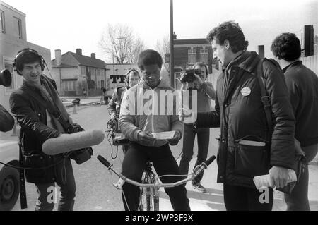 London, England Februar 1983. Peter Tatchell, der Gay-Rights-Aktivist, will auf der Bermondsey durch die Wahl South London in die Labour-Partei als Abgeordneter gewählt werden. Wahlsitzung und Begrüßung im Wahlkreis. Er trägt ein "Gerechtigkeit für die Rentner"-Abzeichen, TV-Nachrichten-Crews folgen ihm. 1980er Jahre HOMER SYKES Stockfoto