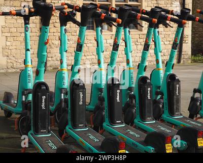 Reihe von hellgrünen West Scoot Elektrorollern, betrieben von der deutschen Firma Tier in James Street West, Bath, Somerset. Nachhaltigkeit, geringe Emissionen. Stockfoto