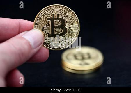 Symbolbild: Eine Hand hält einen Bitcoin - der Bitcoin steht hoch im Kurs. Selbst Finanzdienstleister wie Paypal wollen die Kryptowährung als Zahlung Stockfoto