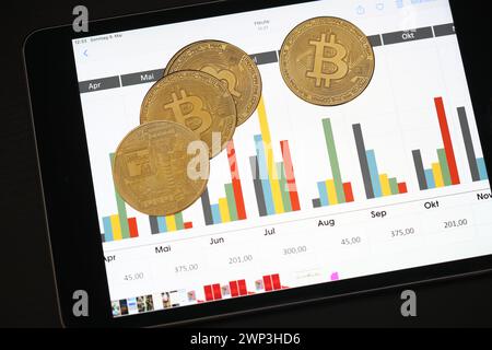 Symbolbild: Bitcoins vor einem Tablet mit Finanzdaten - der Bitcoin steht hoch im Kurs. Selbst Finanzdienstleister wie Paypal wollen die Kryptowährun Stockfoto