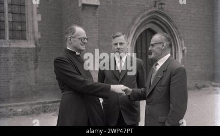 1950er Jahre, ein englischer Geistlicher, Reverend A. S. Wye, vor dem Pfarrhaus, der seine neuen Kirchenwärter in Oxford, England, Großbritannien begrüßt. Im 13. Jahrhundert erschienen Kirchwärter, Mitglieder einer Gemeinde, die von und aus den Gemeindemitgliedern gewählt wurde, um die religiösen Glaubens, die Laien zu vertreten und die Verantwortung für die kirchliche Struktur, Verwaltung und andere Aufgaben zu übernehmen. Stockfoto