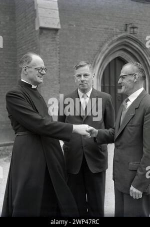 1950er Jahre, ein englischer Geistlicher, Reverend A. S. Wye, vor dem Pfarrhaus, der seine neuen Kirchenwärter in Oxford, England, Großbritannien begrüßt. Im 13. Jahrhundert erschienen Kirchwärter, Mitglieder einer Gemeinde, die von und aus den Gemeindemitgliedern gewählt wurde, um die religiösen Glaubens, die Laien zu vertreten und die Verantwortung für die kirchliche Struktur, Verwaltung und andere Aufgaben zu übernehmen. Stockfoto