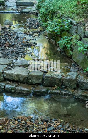 Nahaufnahme eines flachen, von Menschen geschaffenen Baches, der an sonnigen Sommertagen in Südkorea über flache Steine stürzt Stockfoto