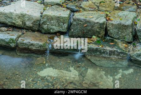 Nahaufnahme eines flachen, von Menschen geschaffenen Baches, der an sonnigen Sommertagen in Südkorea über flache Steine stürzt Stockfoto