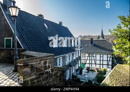 Blick auf eine Gasse mit historischen Fachwerkhäusern und einem Kirchturm im Hintergrund, Graefrath, Solingen, Bergisches Land, Nordrhein-Westfalen Stockfoto