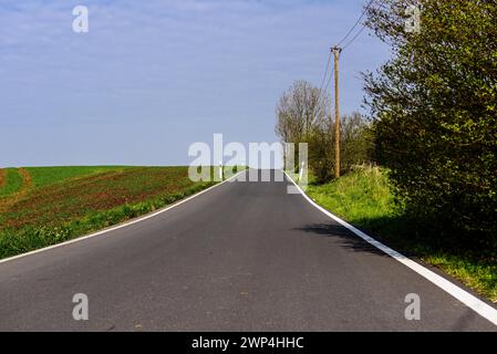 Eine leere Landstraße führt durch eine grüne Landschaft unter klarem blauem Himmel, Nordbahntrasse, Elberfeld, Wuppertal, Bergisches Land, Nord Stockfoto