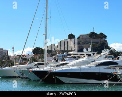 Einige Boote im Hafen von Denia, Spanien, an einem sonnigen Tag. Die alte mittelalterliche Burg befindet sich im Hintergrund. Stockfoto
